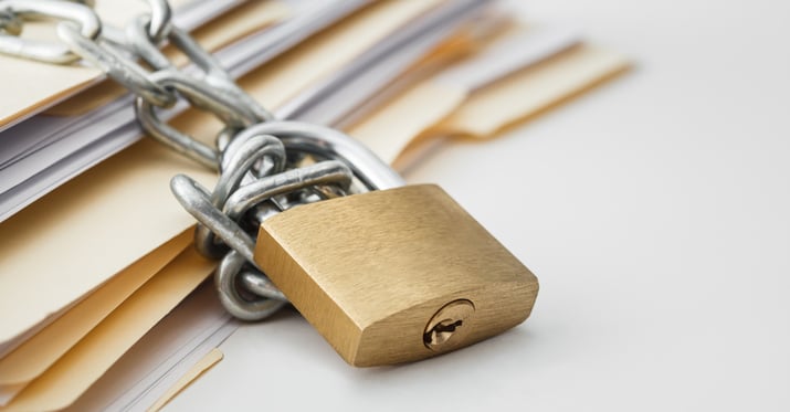 Photo of a padlock chained to blank folders with papers in them.