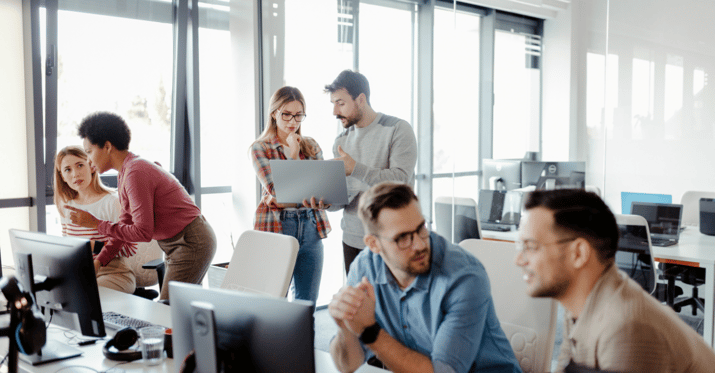 A picture of corporate workers collaborating on laptops in an office setting